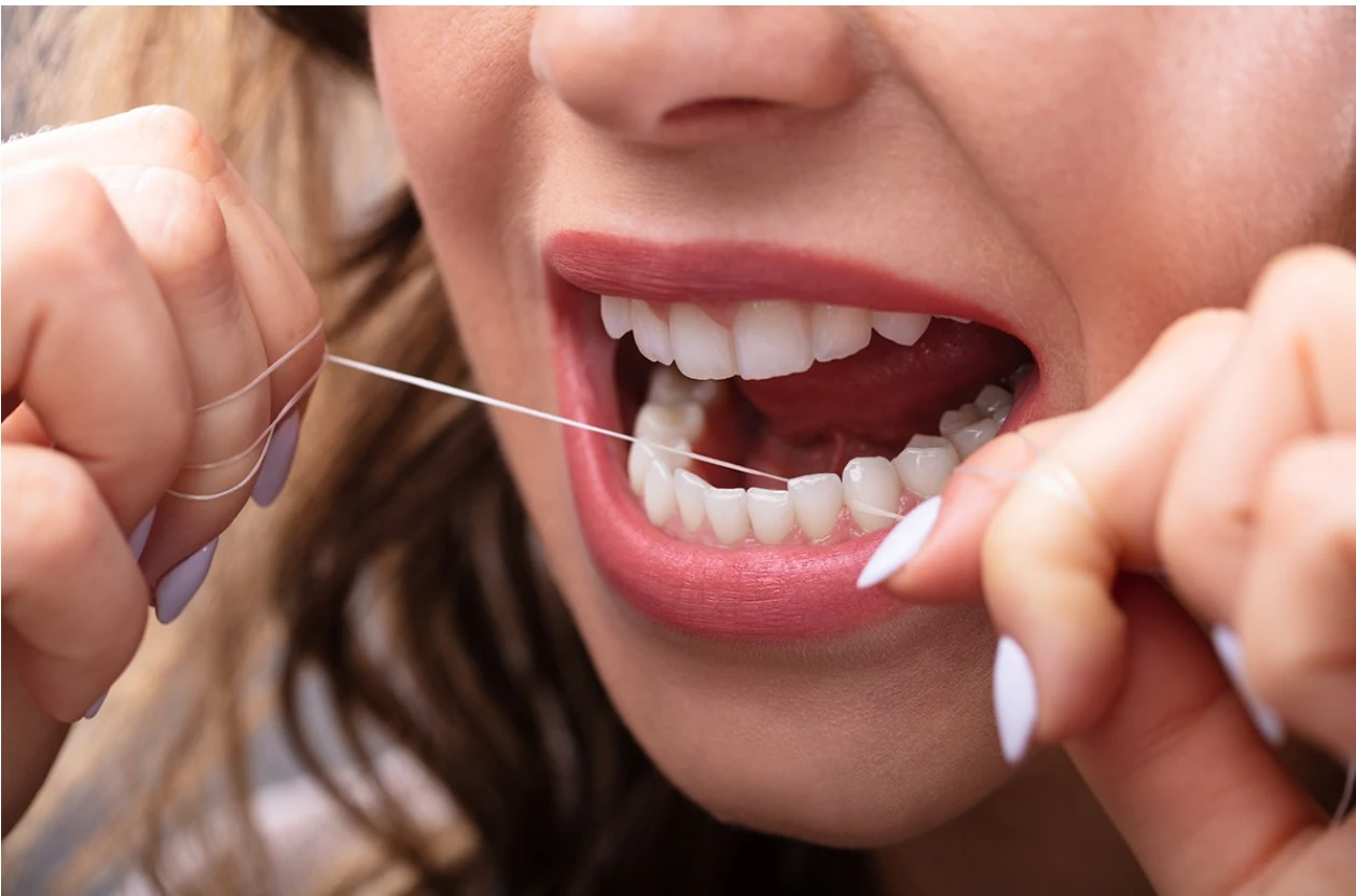 Flossing teeth to remove plaque between teeth